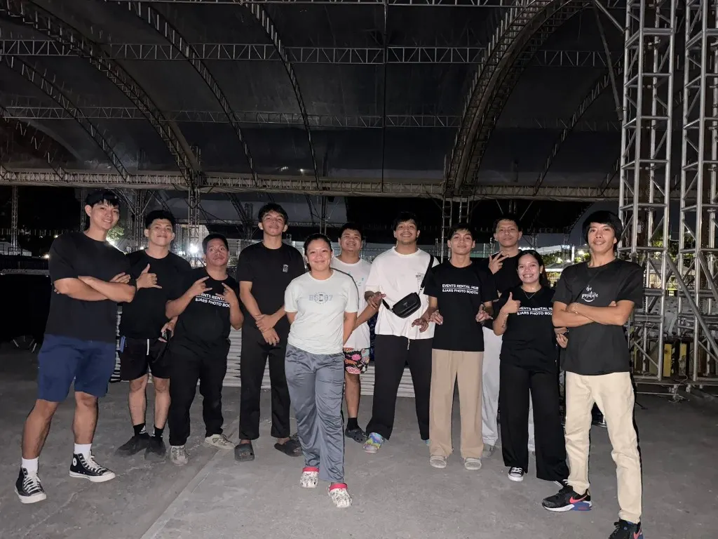 Events Rental Hub team posing under a large metal tent structure after an evening event